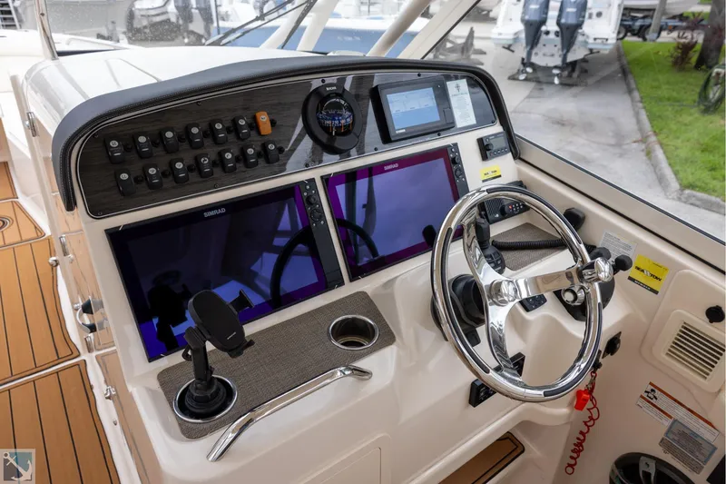 Slide: The Image of 2019 Grady-White Freedom 335 boat dashboard with steering wheel and navigation controls. - 17