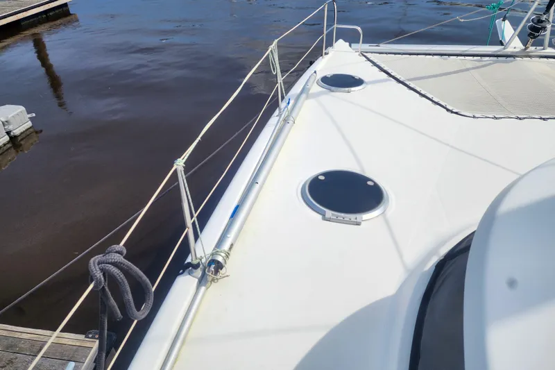 Slide: The Image of 2013 Fountaine Pajot Lipari 41 catamaran deck with hatches and railing, docked by calm water. - 11