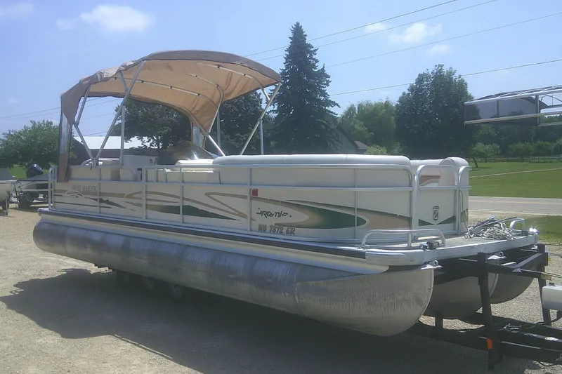 The Image of 1999 Premier 250 Grand Majestic pontoon boat with canopy on trailer, parked outdoors. - 0