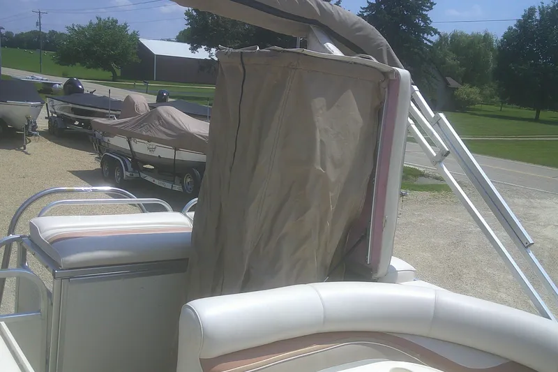 Slide: The Image of 1999 Premier 250 Grand Majestic pontoon boat with covered seating, parked outdoors. - 18