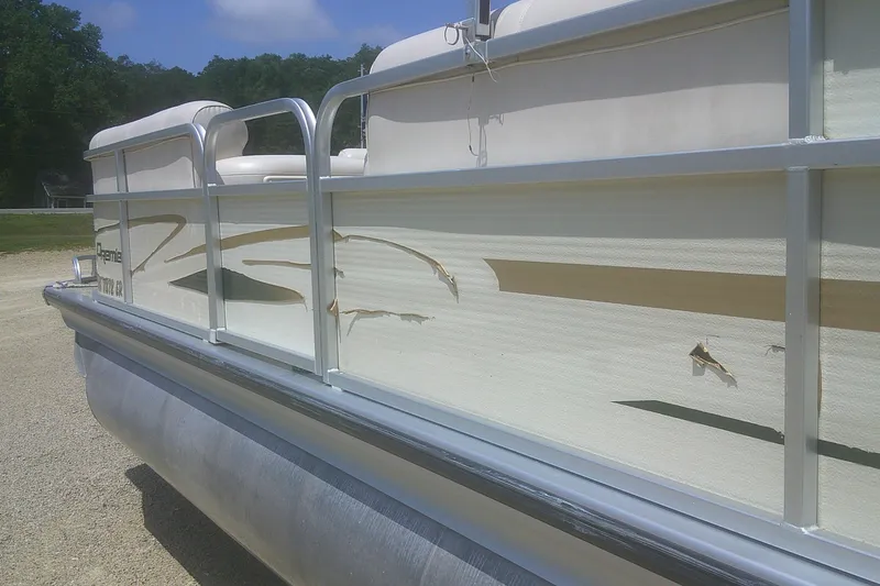 Slide: The Image of Damaged 1999 Premier 250 Grand Majestic pontoon boat with peeling decals and visible wear. - 4