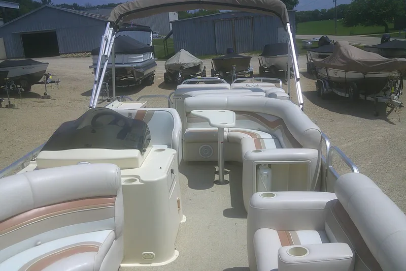Slide: The Image of 1999 Premier 250 Grand Majestic pontoon boat with spacious seating and table, parked outdoors. - 9