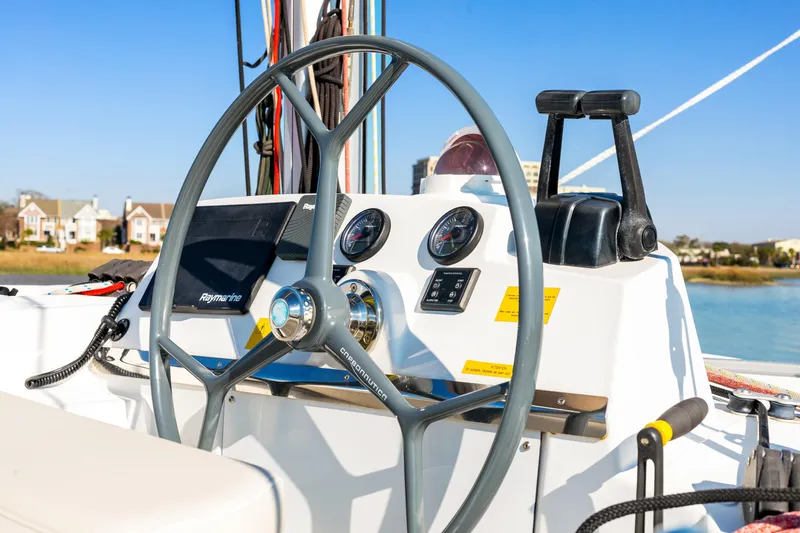 Slide: The Image of Steering wheel and controls of a 2018 Bali 4.0 catamaran, with scenic waterfront view. - 36