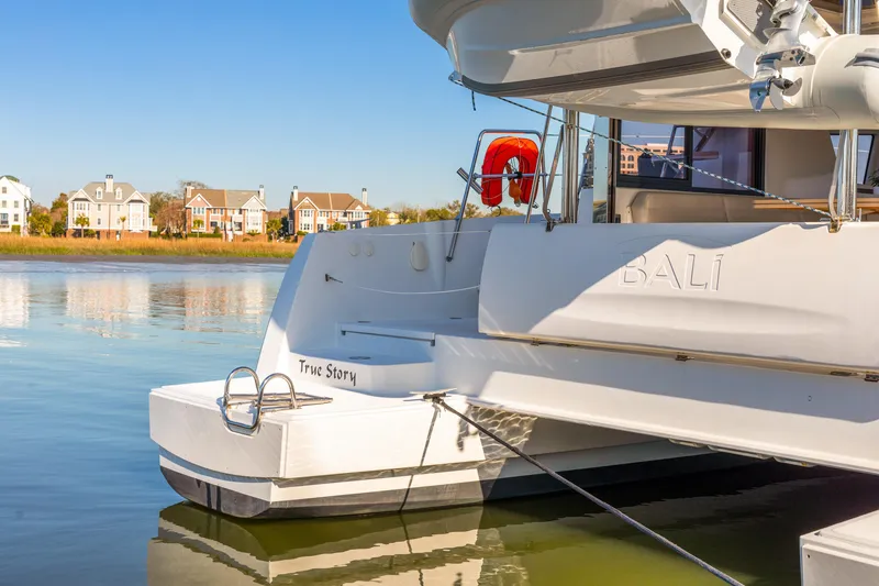 Slide: The Image of 2018 Bali 4.0 catamaran docked near waterfront homes on a sunny day. - 5