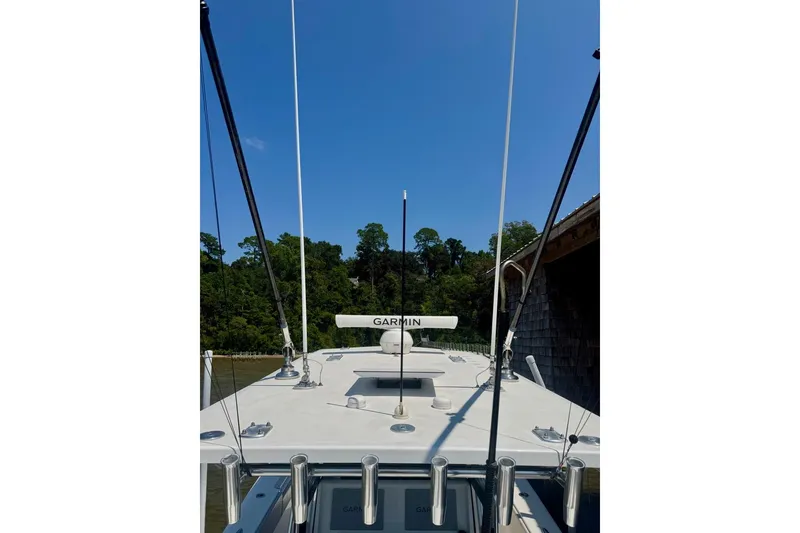 Slide: The Image of 2020 Invincible 36 Open Fisherman boat with Garmin equipment, docked near lush greenery. - 20