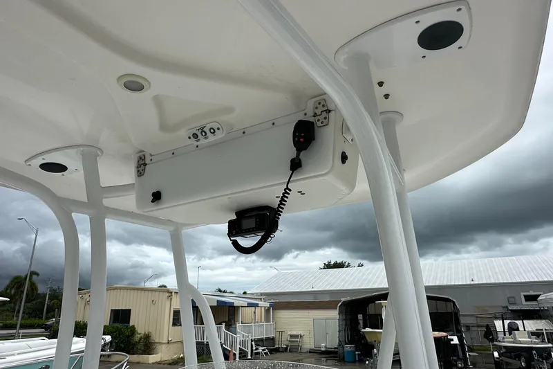 Slide: The Image of 2014 Tidewater 210 CC Adventure boat with T-top and radio equipment under cloudy sky. - 8