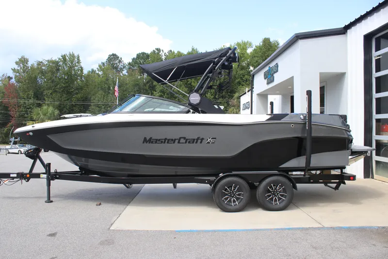 Slide: The Image of 2025 MasterCraft XT24 boat on trailer, parked outside dealership. - 13