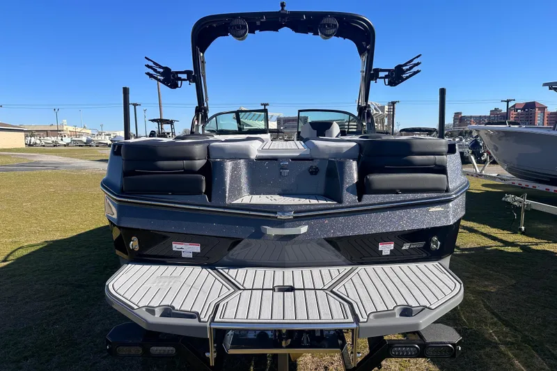 Slide: The Image of 2025 MasterCraft XT24 boat, rear view, on display outdoors under clear blue sky. - 15