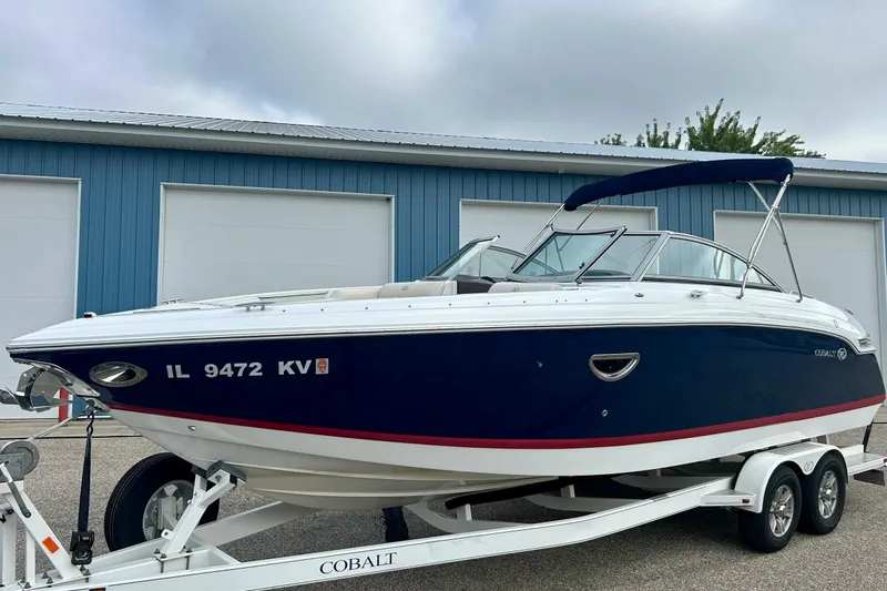 Slide: The Image of 2010 Cobalt 276 boat on trailer, blue and white, parked near blue building. - 16