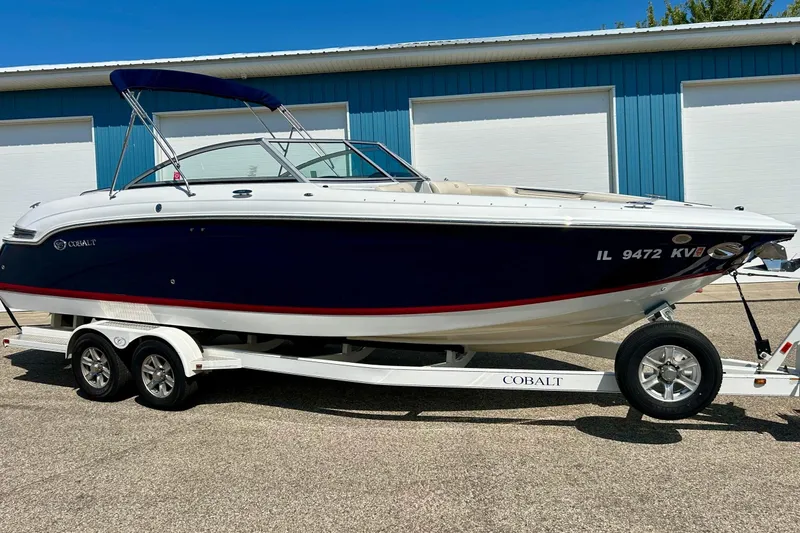 Slide: The Image of 2010 Cobalt 276 boat on trailer, blue and white design, parked outdoors. - 32