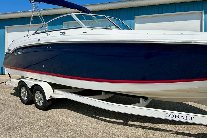 Slide: The Image of 2010 Cobalt 276 boat on trailer, blue and white design, parked outdoors. - 35
