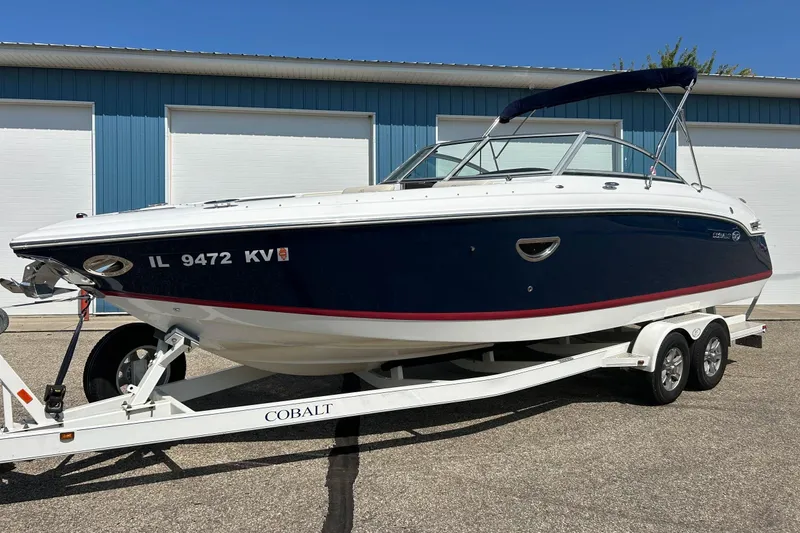 Slide: The Image of 2010 Cobalt 276 boat on trailer, parked outside blue building. - 43
