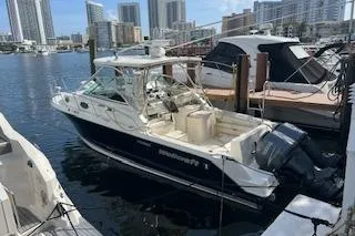The Image of 2010 Wellcraft 290 Coastal Walk-Around boat docked in marina with city skyline. - 1