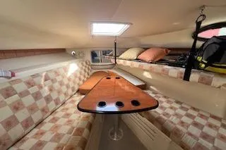 Slide: The Image of 2010 Wellcraft 290 Coastal Walk-Around cabin interior with checkered seating and wooden table. - 10