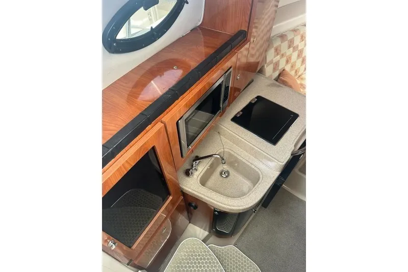 Slide: The Image of 2010 Wellcraft 290 Coastal Walk-Around interior with kitchenette, sink, and wooden cabinetry. - 12