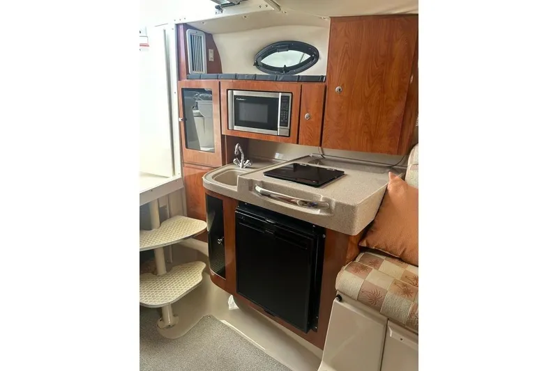Slide: The Image of 2010 Wellcraft 290 Coastal Walk-Around interior with kitchenette, microwave, and seating area. - 15