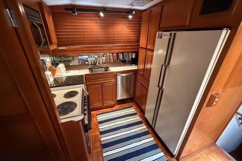 Slide: The Image of 1989 Jefferson Marquessa 52 yacht kitchen with wooden cabinets, modern appliances, and striped rug. - 15