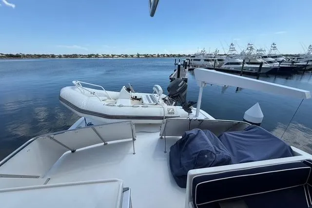 Slide: The Image of 1989 Jefferson Marquessa 52 yacht with dinghy, docked at marina under clear blue sky. - 7