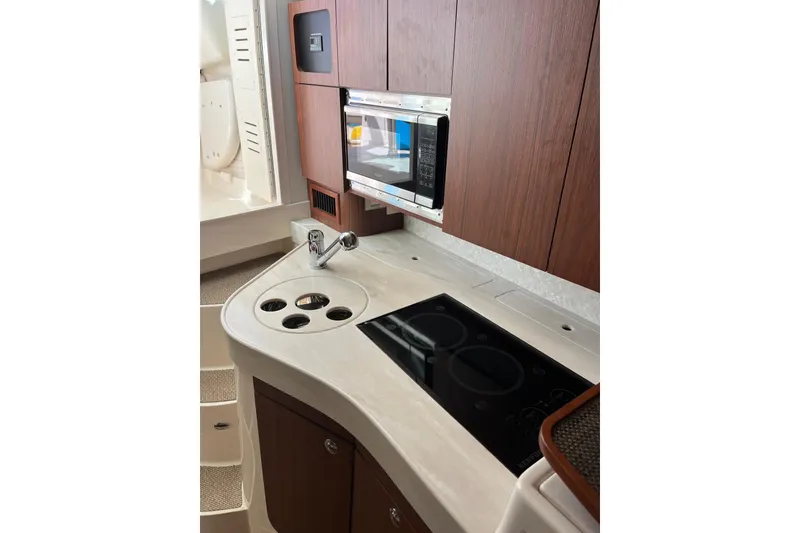 Slide: The Image of 2020 Grady-White Express 330 boat kitchen with microwave, stove, and wooden cabinets. - 19