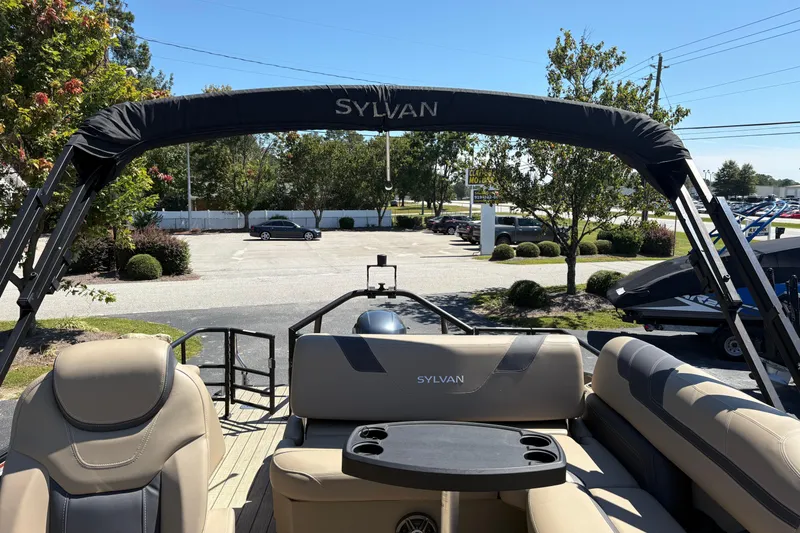 Slide: The Image of 2024 Sylvan L3 CLZ pontoon boat with beige seating and black canopy in a parking lot. - 16