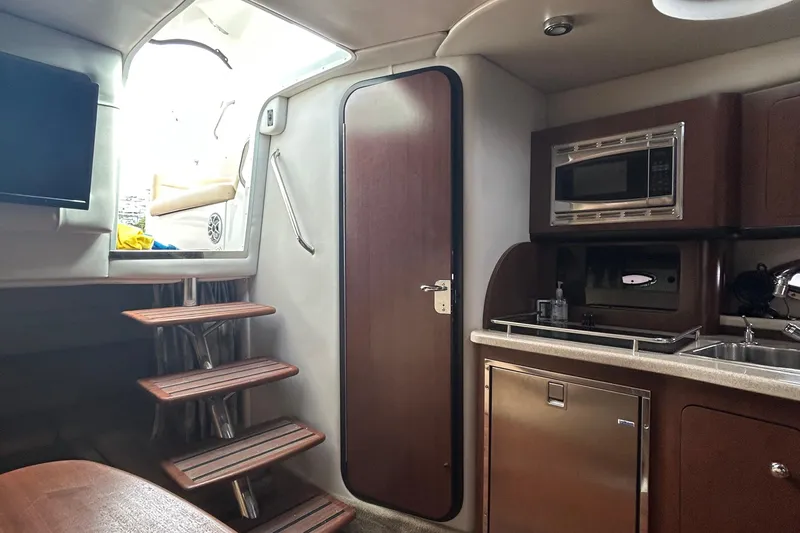 Slide: The Image of Interior of 2015 Crownline 350 SY yacht featuring kitchenette, stairs, and door. - 17