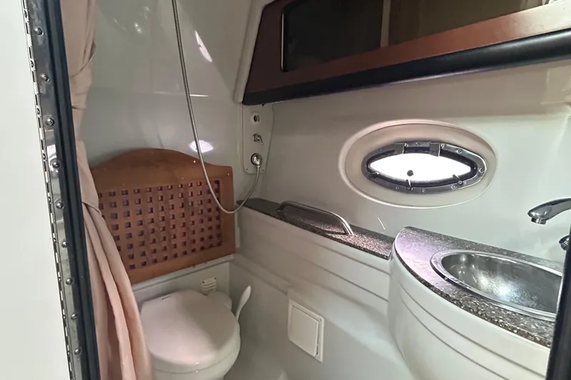 Slide: The Image of 2015 Crownline 350 SY yacht bathroom with sink, toilet, and porthole window. - 18