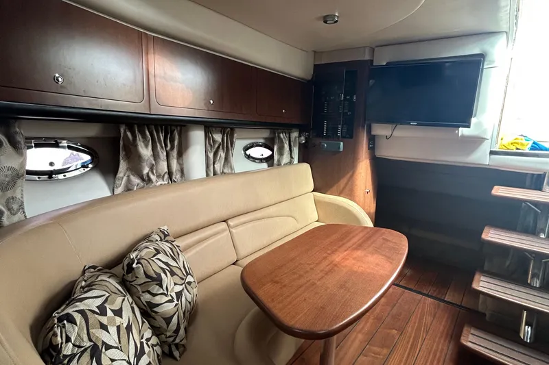 Slide: The Image of 2015 Crownline 350 SY yacht interior with cozy seating, wooden table, and mounted TV. - 22