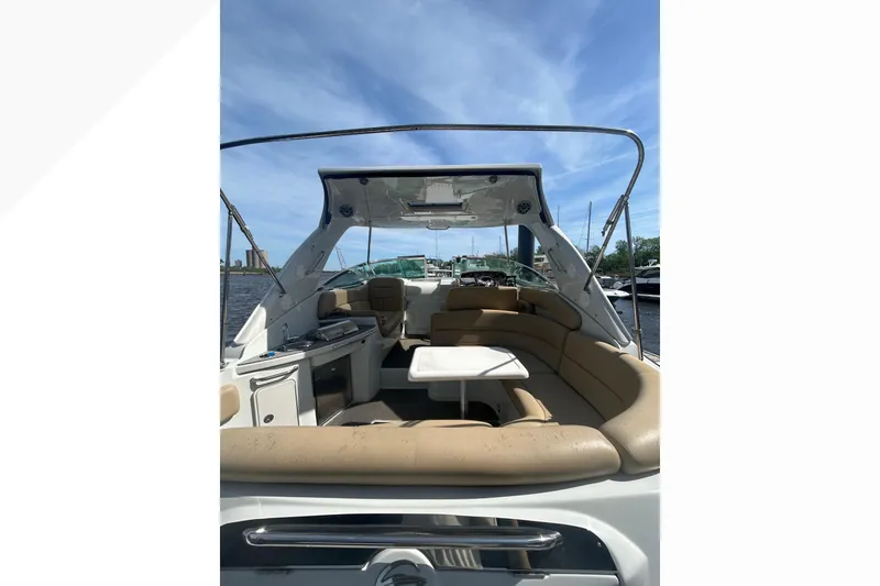 Slide: The Image of 2015 Crownline 350 SY boat interior with seating and table under blue sky. - 45