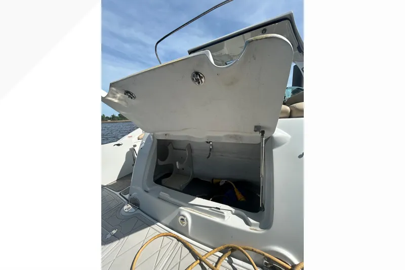 Slide: The Image of Open storage compartment on 2015 Crownline 350 SY boat, docked by the water. - 47