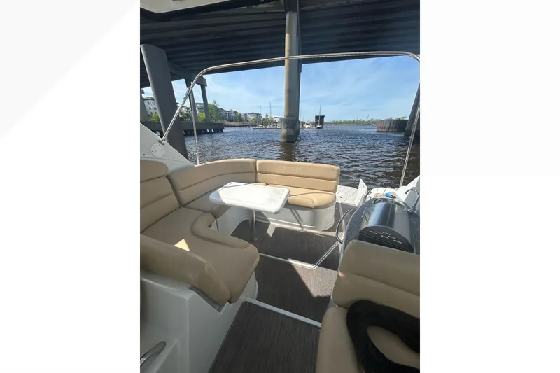 Slide: The Image of 2015 Crownline 350 SY boat interior with tan seating, table, and waterfront view. - 55