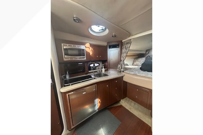 Slide: The Image of 2015 Crownline 350 SY yacht interior with kitchenette and cozy sleeping area. - 58