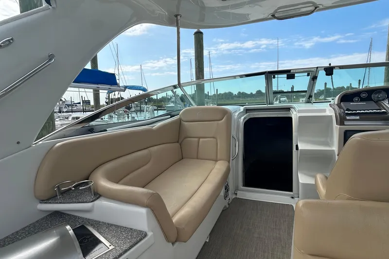 Slide: The Image of 2015 Crownline 350 SY boat interior with beige seating and marina view. - 6