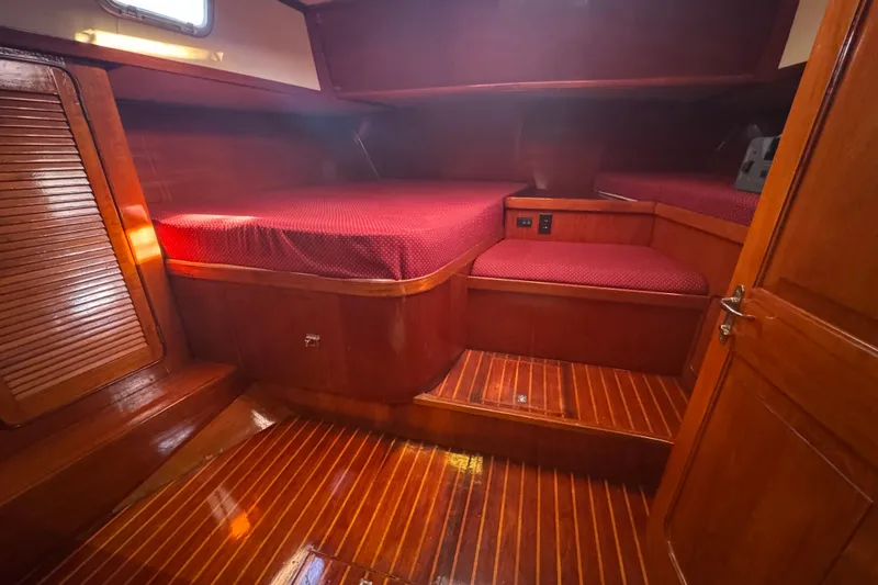 Slide: The Image of 1981 Gulfstar 60 CC yacht cabin with polished wood and red bedding. - 7