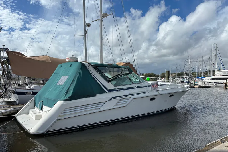 Slide: The Image of 1991 Trojan 12 Meter Express 400 yacht docked, featuring a green canopy, under a partly cloudy sky. - 1