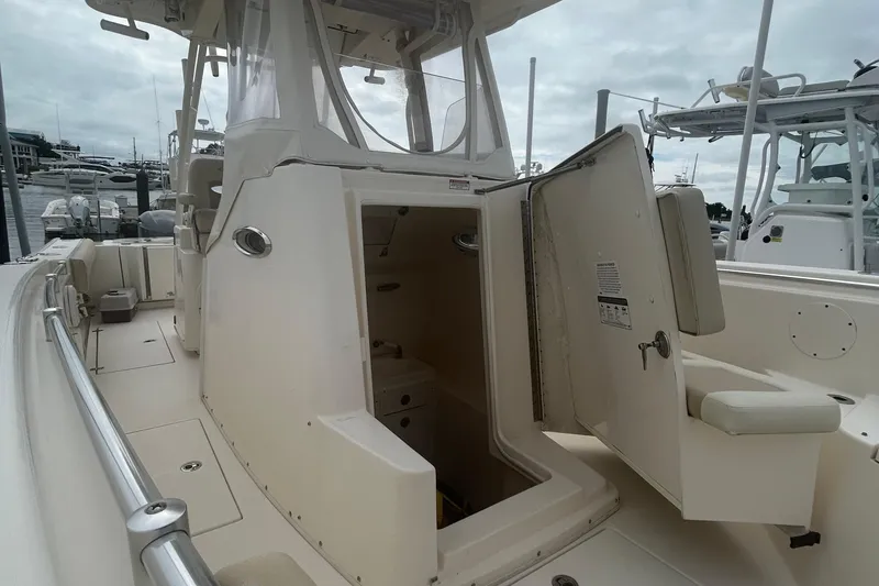 Slide: The Image of 2016 Cobia 296 Center Console boat with open storage compartment, docked at marina. - 18
