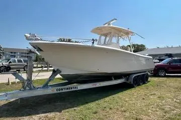 Slide: The Image of 2016 Cobia 296 Center Console boat on trailer, parked outdoors. - 2