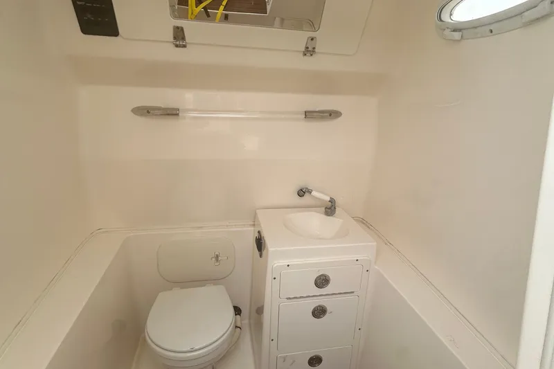 Slide: The Image of 2016 Cobia 296 Center Console boat bathroom with toilet, sink, and storage drawers. - 21