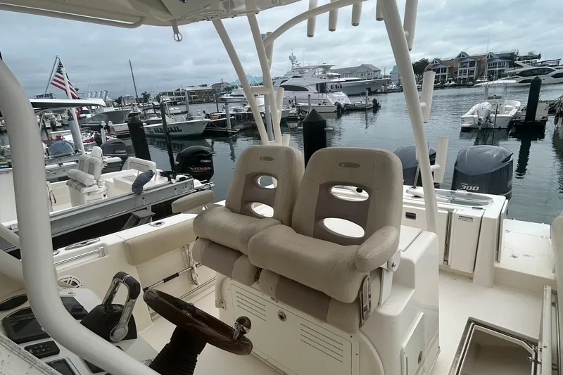 Slide: The Image of 2016 Cobia 296 Center Console boat interior at marina, featuring dual seats and steering wheel. - 24