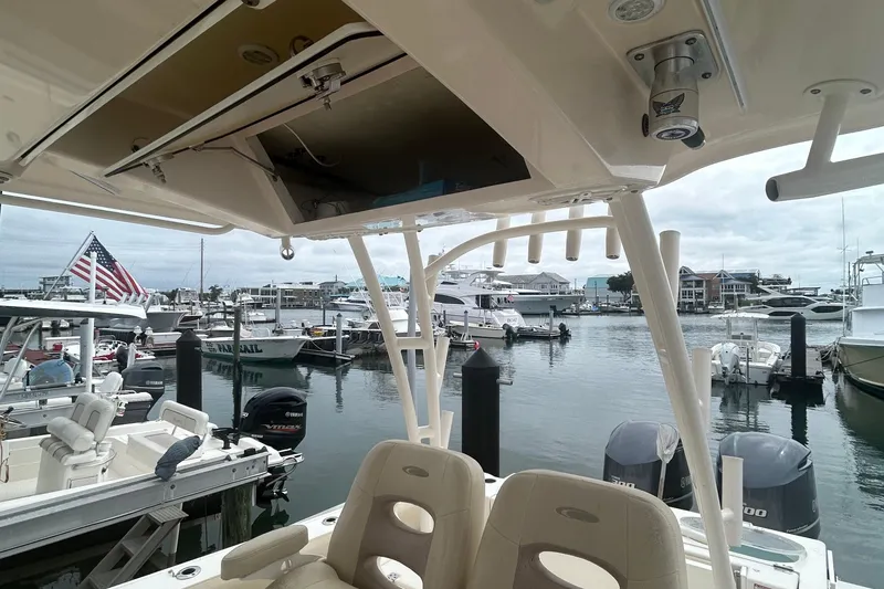 Slide: The Image of 2016 Cobia 296 Center Console boat docked at a marina with other vessels. - 25