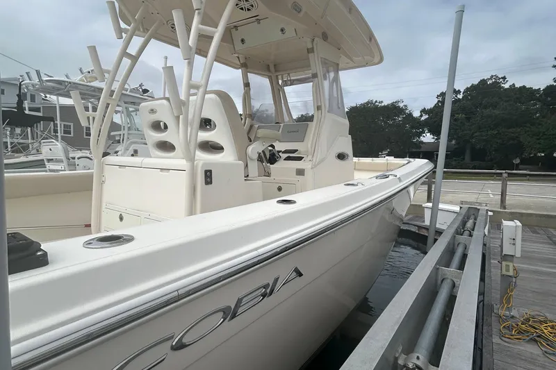 Slide: The Image of 2016 Cobia 296 Center Console boat docked, showcasing sleek design and spacious deck. - 34