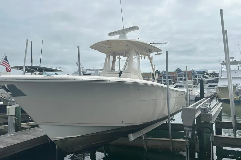 Slide: The Image of 2016 Cobia 296 Center Console boat docked at marina under cloudy sky. - 36