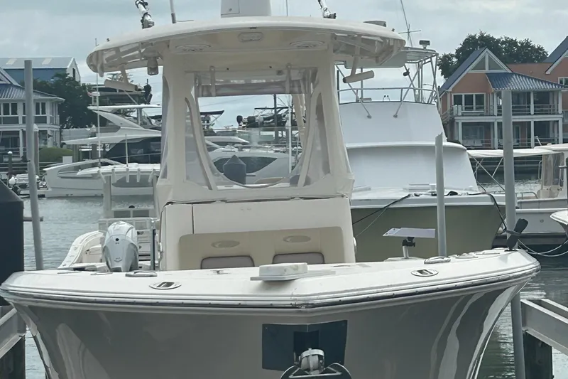 Slide: The Image of 2016 Cobia 296 Center Console boat docked in a marina with waterfront homes. - 38