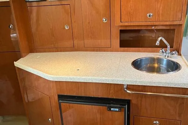 Slide: The Image of 2007 Regal 3060 Window Express boat interior with wooden cabinets and compact kitchenette. - 15