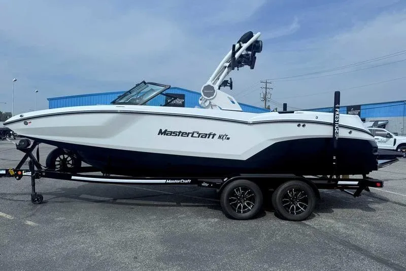 The Image of 2026 MasterCraft NXT22 boat on trailer, parked outdoors, side view. - 0