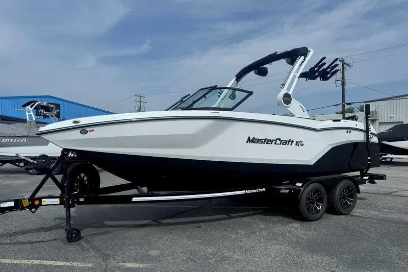 Slide: The Image of 2026 MasterCraft NXT22 boat on trailer, parked outdoors under clear sky. - 2