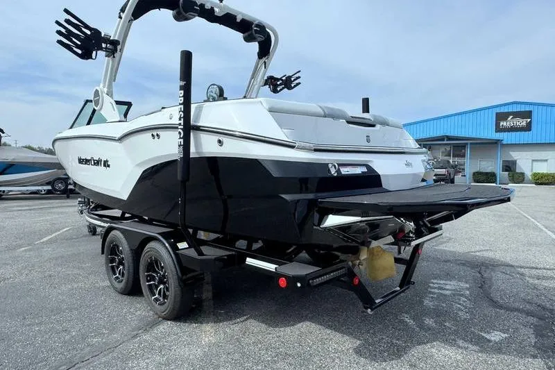 Slide: The Image of 2026 MasterCraft NXT22 boat on trailer, parked outside a dealership. - 5