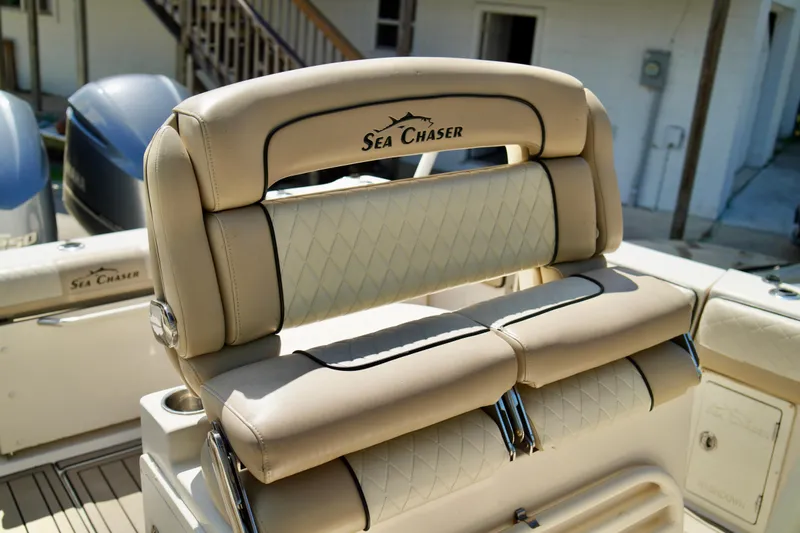 Slide: The Image of 2019 Carolina Skiff Sea Chaser 27 HFC boat seating with beige upholstery and logo. - 18