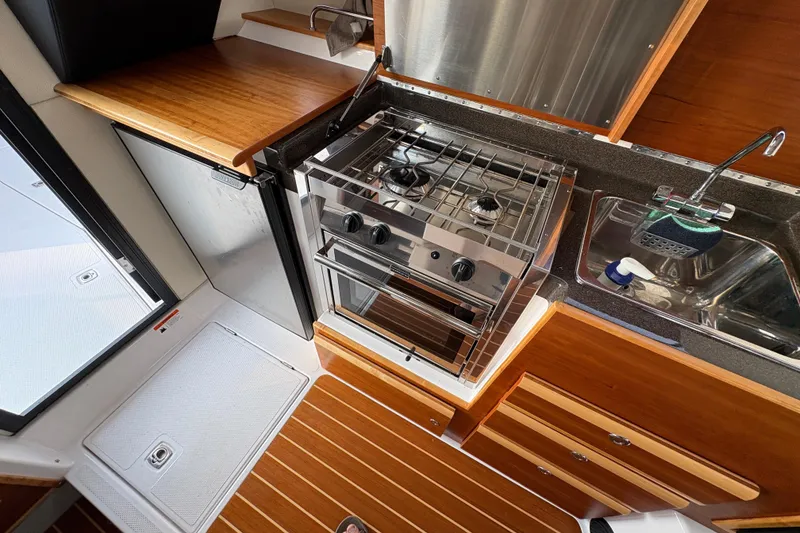 Slide: The Image of 2018 Cutwater C-30 CB boat kitchen with stove, sink, and wooden cabinetry. - 41
