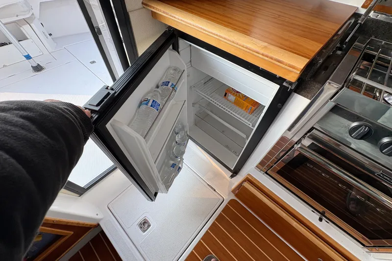 Slide: The Image of 2018 Cutwater C-30 CB boat interior with open mini fridge and wooden countertop. - 54