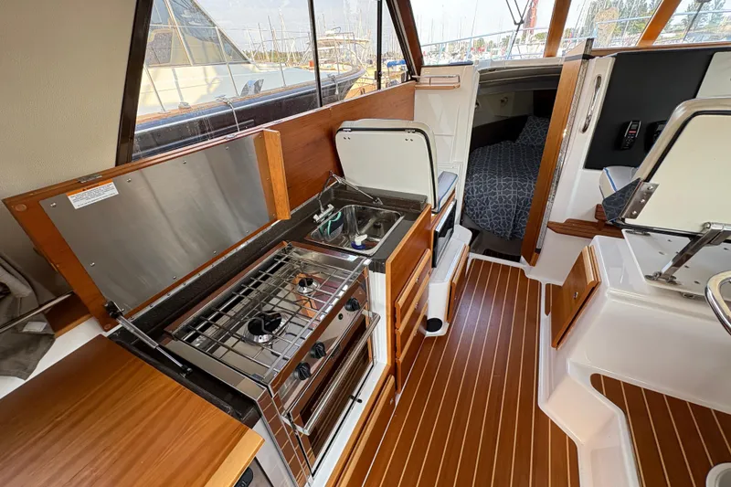 Slide: The Image of 2018 Cutwater C-30 CB interior with compact kitchen, stove, sink, and cozy cabin area. - 55